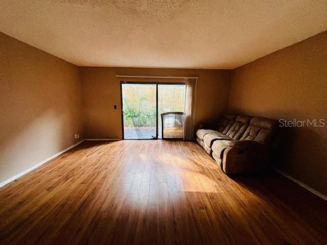 unfurnished living room with wood-type flooring and a textured ceiling