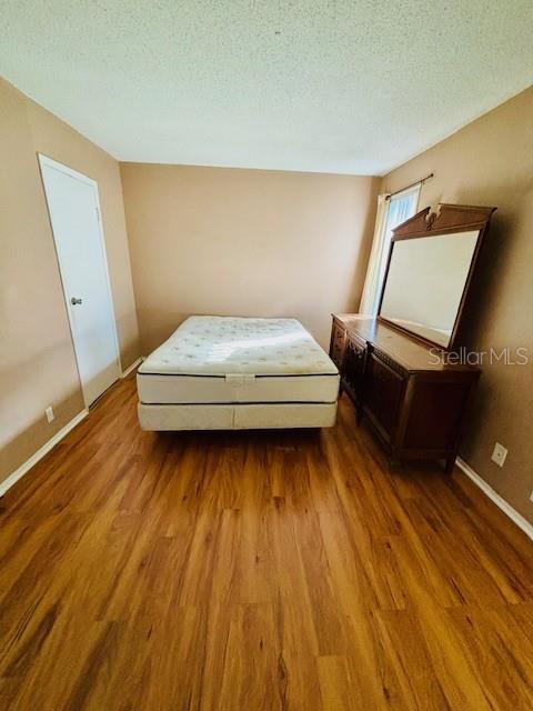 unfurnished bedroom with hardwood / wood-style flooring and a textured ceiling