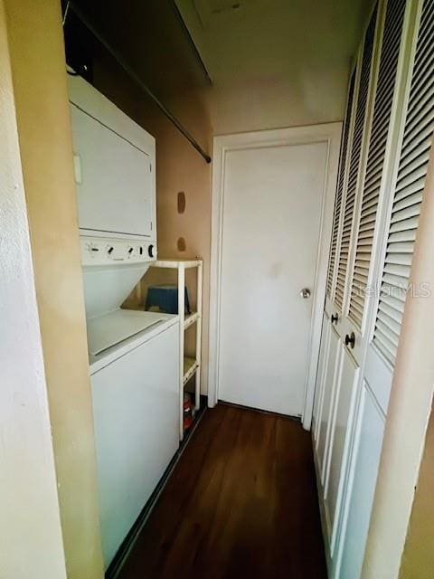 clothes washing area with dark wood-type flooring and stacked washer and clothes dryer