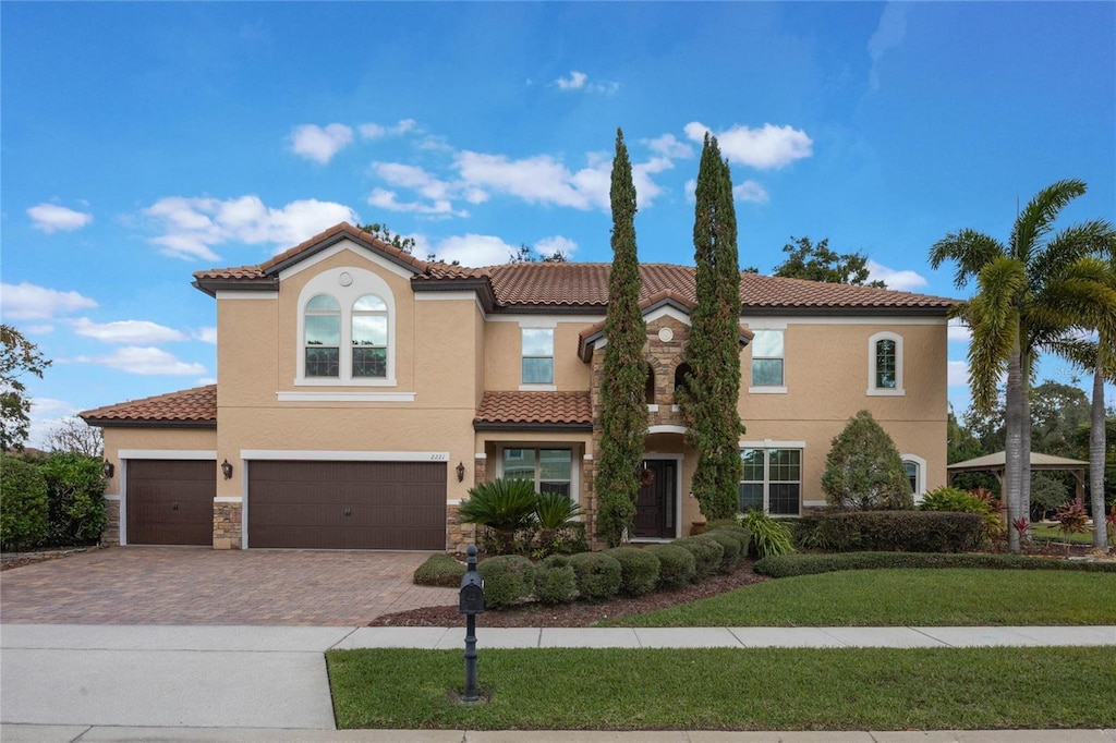 mediterranean / spanish-style house with a garage and a front lawn