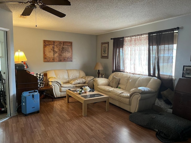 living room with hardwood / wood-style floors, a textured ceiling, and ceiling fan