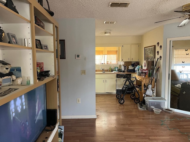 kitchen with sink, dishwasher, a textured ceiling, and light wood-type flooring