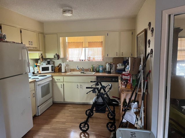 kitchen featuring a textured ceiling, sink, light hardwood / wood-style floors, and white appliances