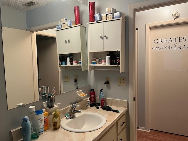 bathroom featuring hardwood / wood-style floors, vanity, and a textured ceiling