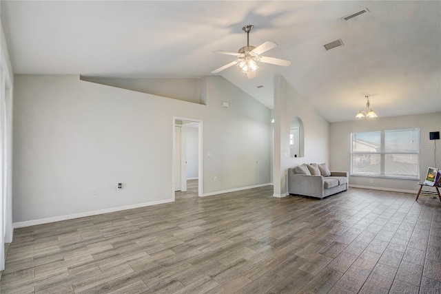 unfurnished living room with ceiling fan with notable chandelier and vaulted ceiling