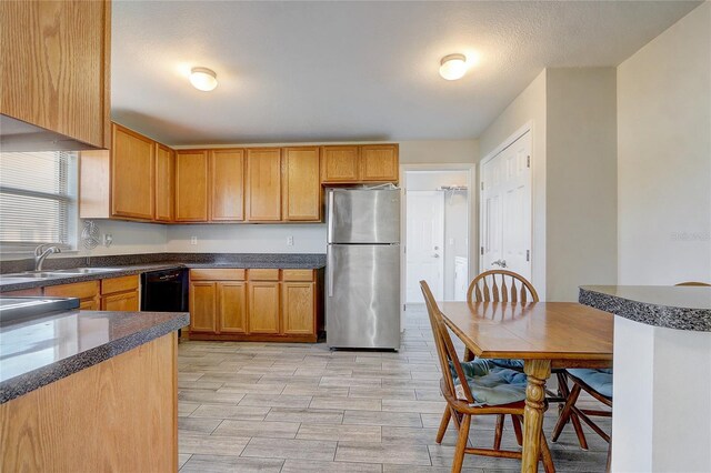 kitchen featuring dishwasher, stainless steel fridge, a textured ceiling, and sink