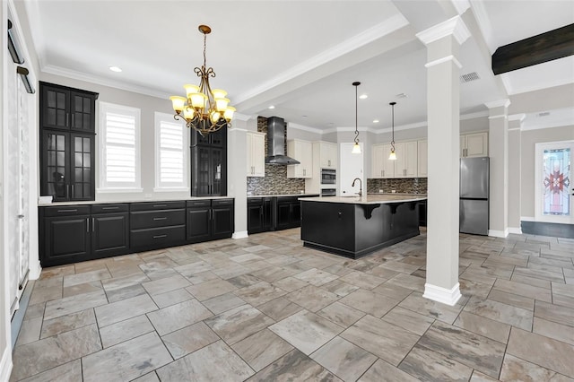 kitchen featuring sink, wall chimney exhaust hood, decorative backsplash, an island with sink, and stainless steel appliances