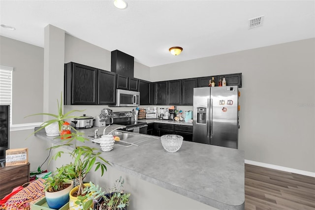 kitchen with sink, kitchen peninsula, dark wood-type flooring, and appliances with stainless steel finishes