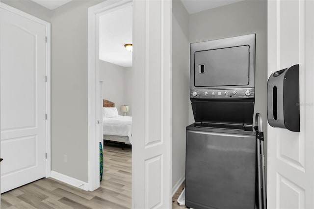 laundry room with light hardwood / wood-style floors and stacked washer and clothes dryer