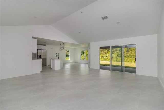 unfurnished living room featuring sink, high vaulted ceiling, and light tile patterned floors