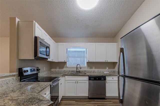 kitchen with light stone countertops, stainless steel appliances, sink, dark hardwood / wood-style floors, and white cabinetry