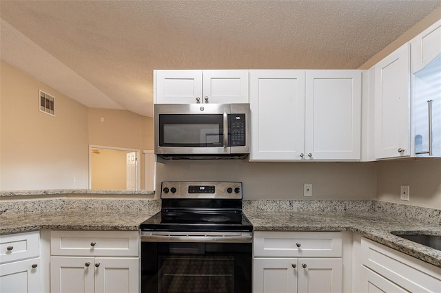 kitchen with light stone counters, white cabinets, a textured ceiling, and appliances with stainless steel finishes