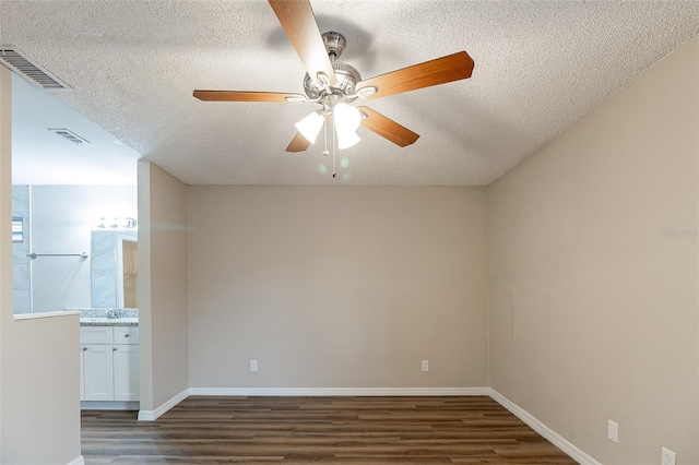 unfurnished room with a textured ceiling, ceiling fan, and dark wood-type flooring