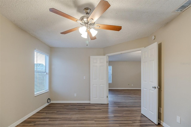 empty room with a textured ceiling, dark hardwood / wood-style flooring, and ceiling fan