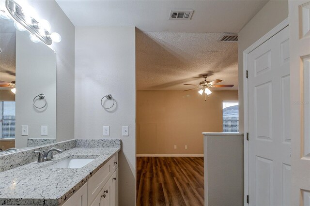 bathroom with vanity, hardwood / wood-style floors, a textured ceiling, and ceiling fan