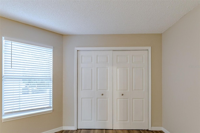 unfurnished bedroom featuring hardwood / wood-style floors, a textured ceiling, and a closet