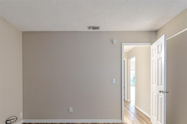 empty room with a textured ceiling and light wood-type flooring