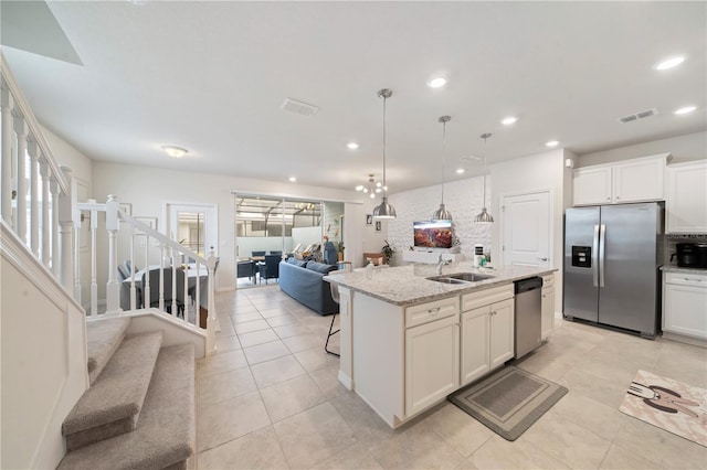 kitchen with white cabinets, sink, an island with sink, appliances with stainless steel finishes, and light stone counters