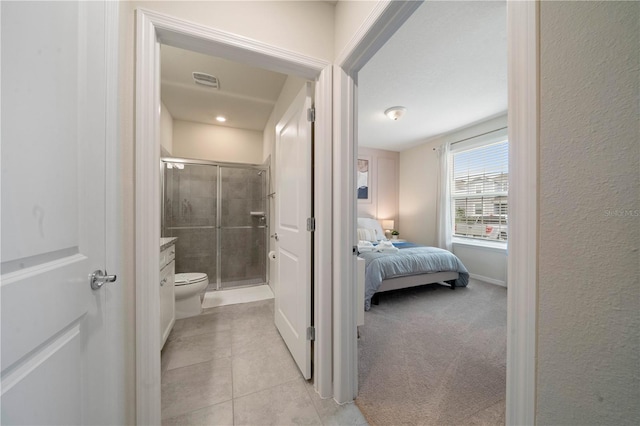 bathroom featuring tile patterned flooring, toilet, and a shower with door