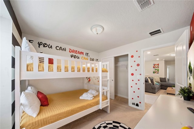 bedroom featuring light colored carpet, a textured ceiling, and a closet