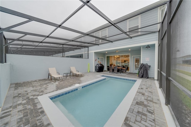 view of pool featuring glass enclosure and a patio area