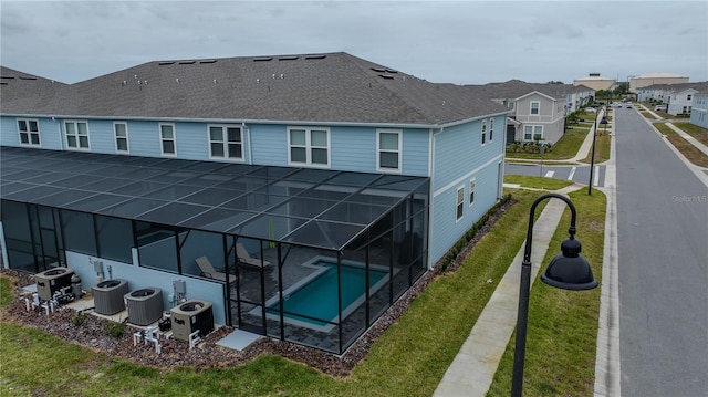 rear view of house featuring a covered pool, glass enclosure, and central AC unit