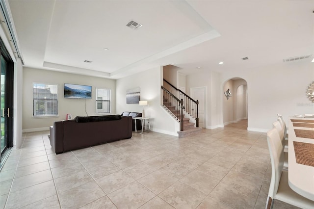 living room with light tile patterned floors and a tray ceiling