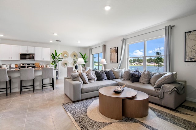 living room featuring a water view and light tile patterned floors