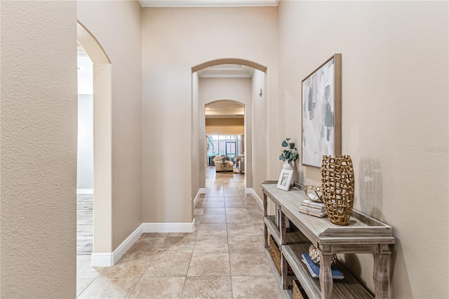 corridor featuring crown molding and light tile patterned floors