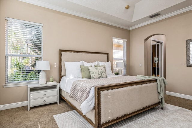 bedroom with ornamental molding, light carpet, and a tray ceiling