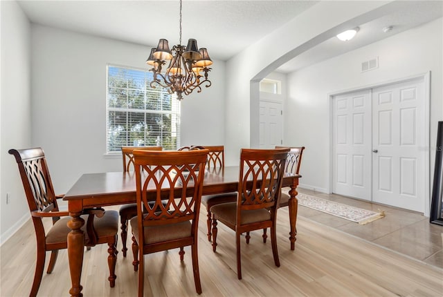 dining room featuring a textured ceiling, light hardwood / wood-style floors, and an inviting chandelier