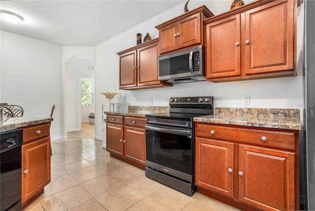 kitchen featuring light stone countertops, light tile patterned floors, black appliances, and a textured ceiling