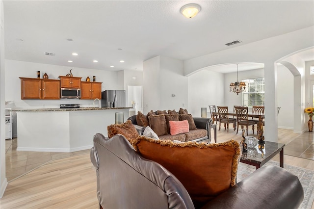 living room with a chandelier, sink, and light hardwood / wood-style floors