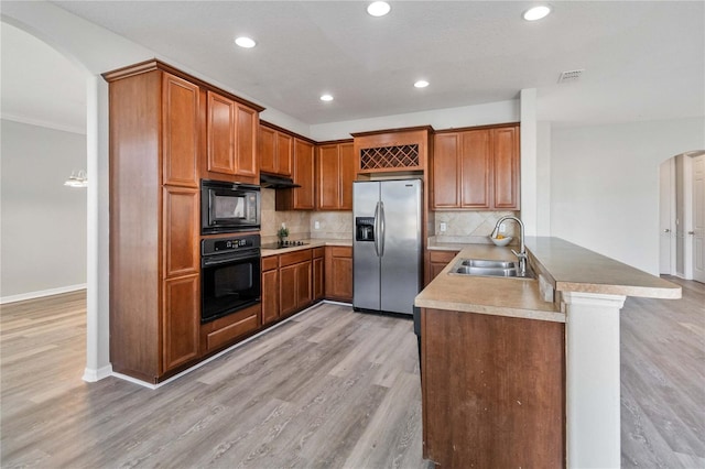 kitchen with black appliances, sink, light hardwood / wood-style flooring, tasteful backsplash, and kitchen peninsula