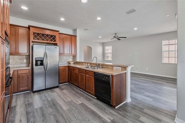 kitchen featuring sink, tasteful backsplash, dark hardwood / wood-style flooring, kitchen peninsula, and appliances with stainless steel finishes