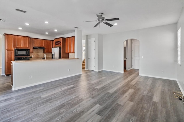 kitchen featuring decorative backsplash, ceiling fan, dark wood-type flooring, and black appliances