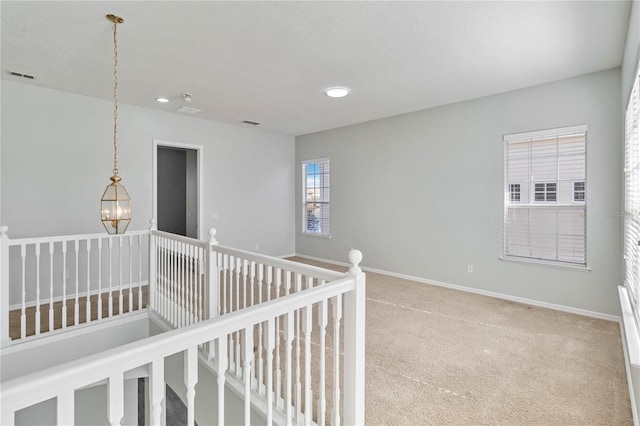 corridor featuring a notable chandelier and carpet floors