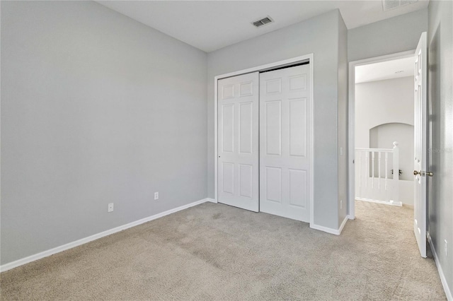 unfurnished bedroom featuring light carpet and a closet