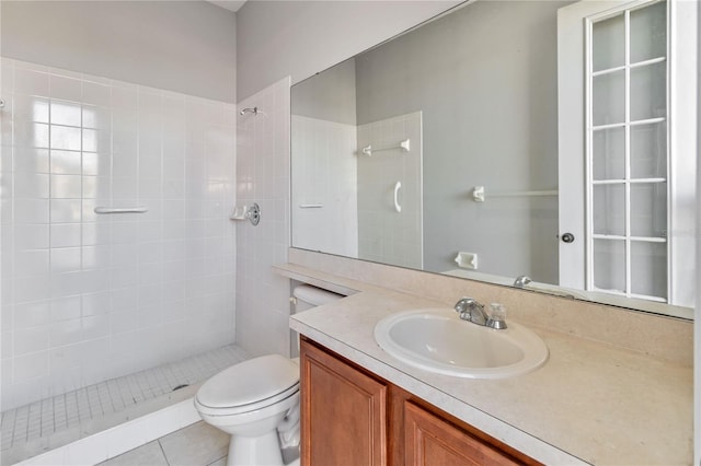 bathroom with tile patterned floors, vanity, a tile shower, and toilet