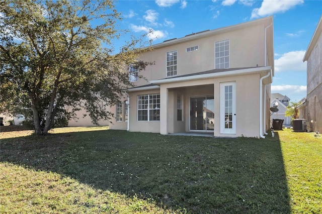 rear view of house featuring central AC unit and a lawn