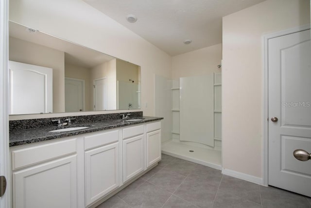 bathroom with double vanity, tile patterned flooring, walk in shower, and a sink