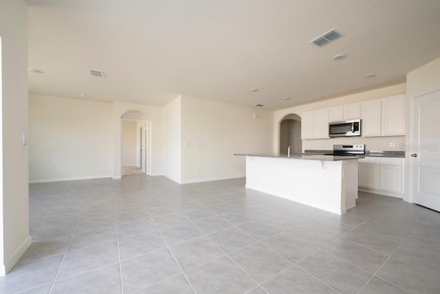 kitchen featuring appliances with stainless steel finishes, arched walkways, open floor plan, and visible vents