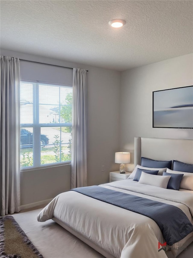 bedroom with a textured ceiling and baseboards