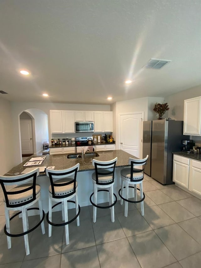 kitchen featuring a sink, stainless steel appliances, white cabinetry, and a breakfast bar area