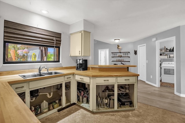 kitchen featuring butcher block counters, sink, cream cabinetry, and washer / dryer