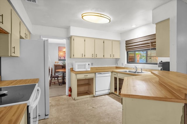 kitchen with kitchen peninsula, cream cabinets, white appliances, and sink