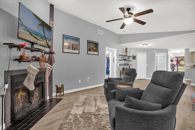 living room with hardwood / wood-style floors, ceiling fan, a fireplace, and vaulted ceiling