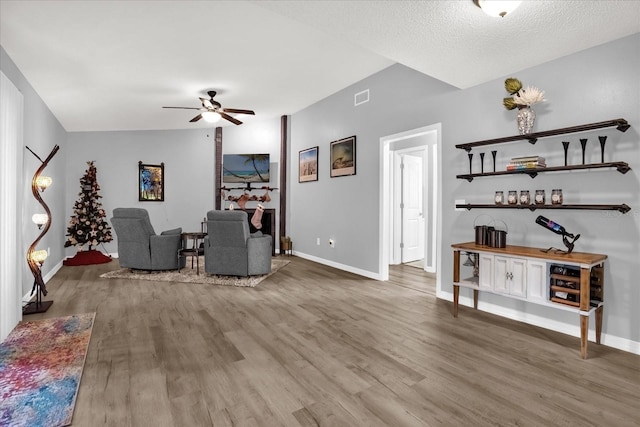 living room with a textured ceiling, hardwood / wood-style flooring, and ceiling fan