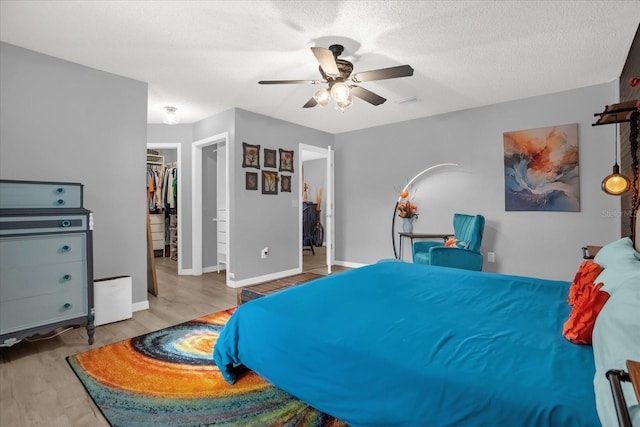 bedroom featuring ceiling fan, light hardwood / wood-style floors, a walk in closet, and a closet