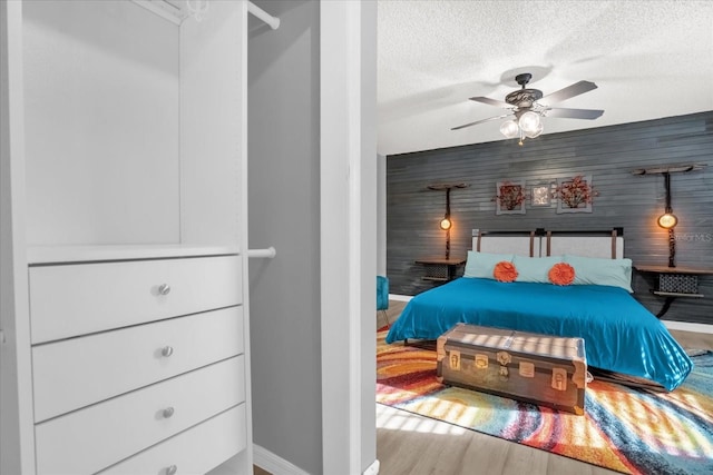 bedroom with hardwood / wood-style floors, ceiling fan, and a textured ceiling